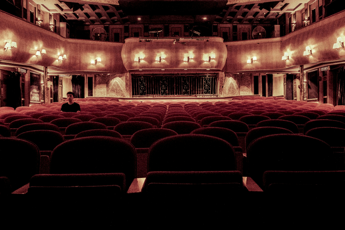 Empty theatre with one singular person sitting towards the left.